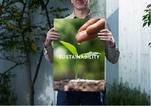 image of a man holding a poster board of a plant with the word sustainability listed in front of it