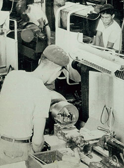 Photo of early TOTO Factory. Worker using a lathe type machine.