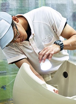 Photo of TOTO worker inspecting a toilet bowl for errors.