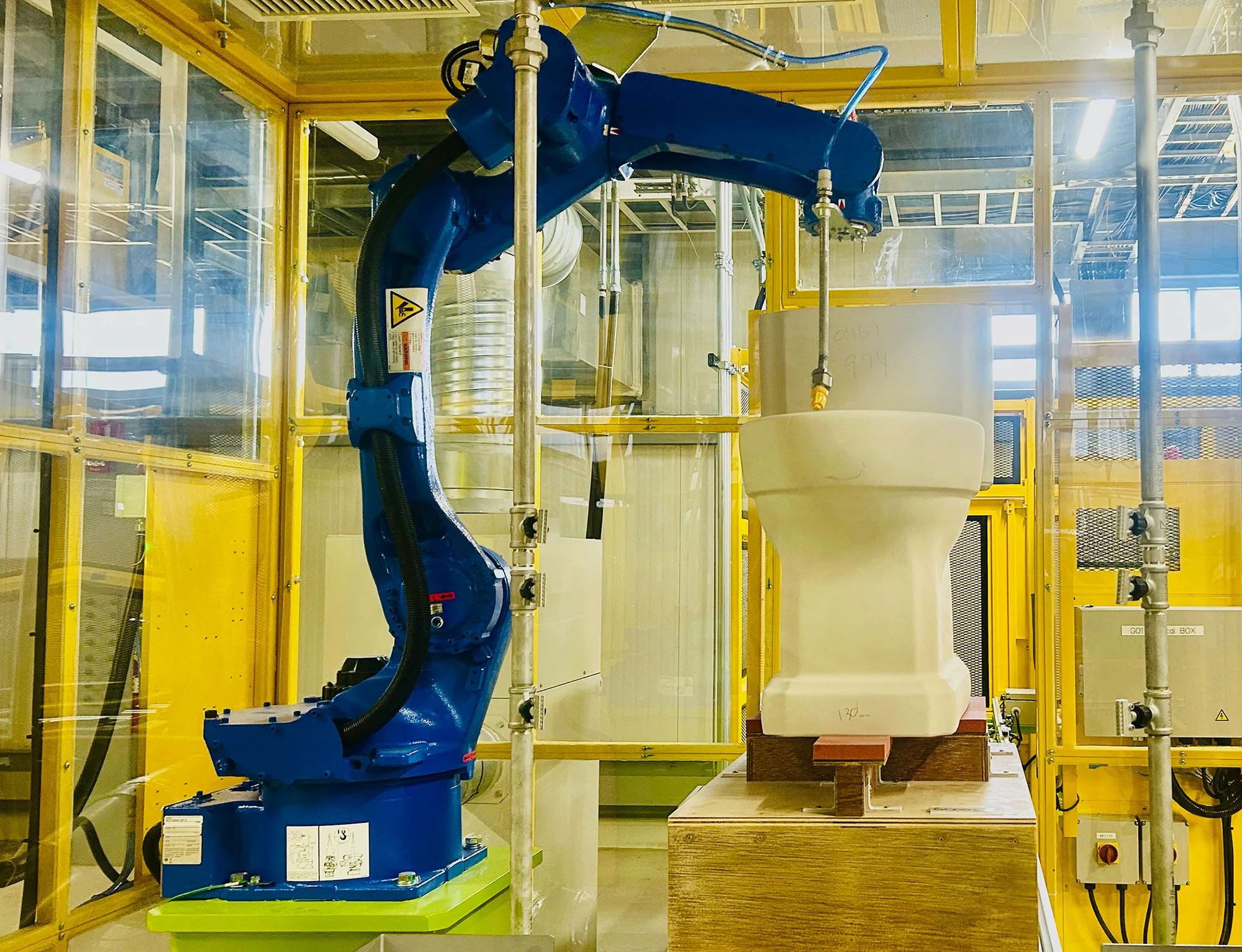 Robotic system removes dust and excess glaze from a one-piece toilet at TOTO’s high-tech Georgia production plant.