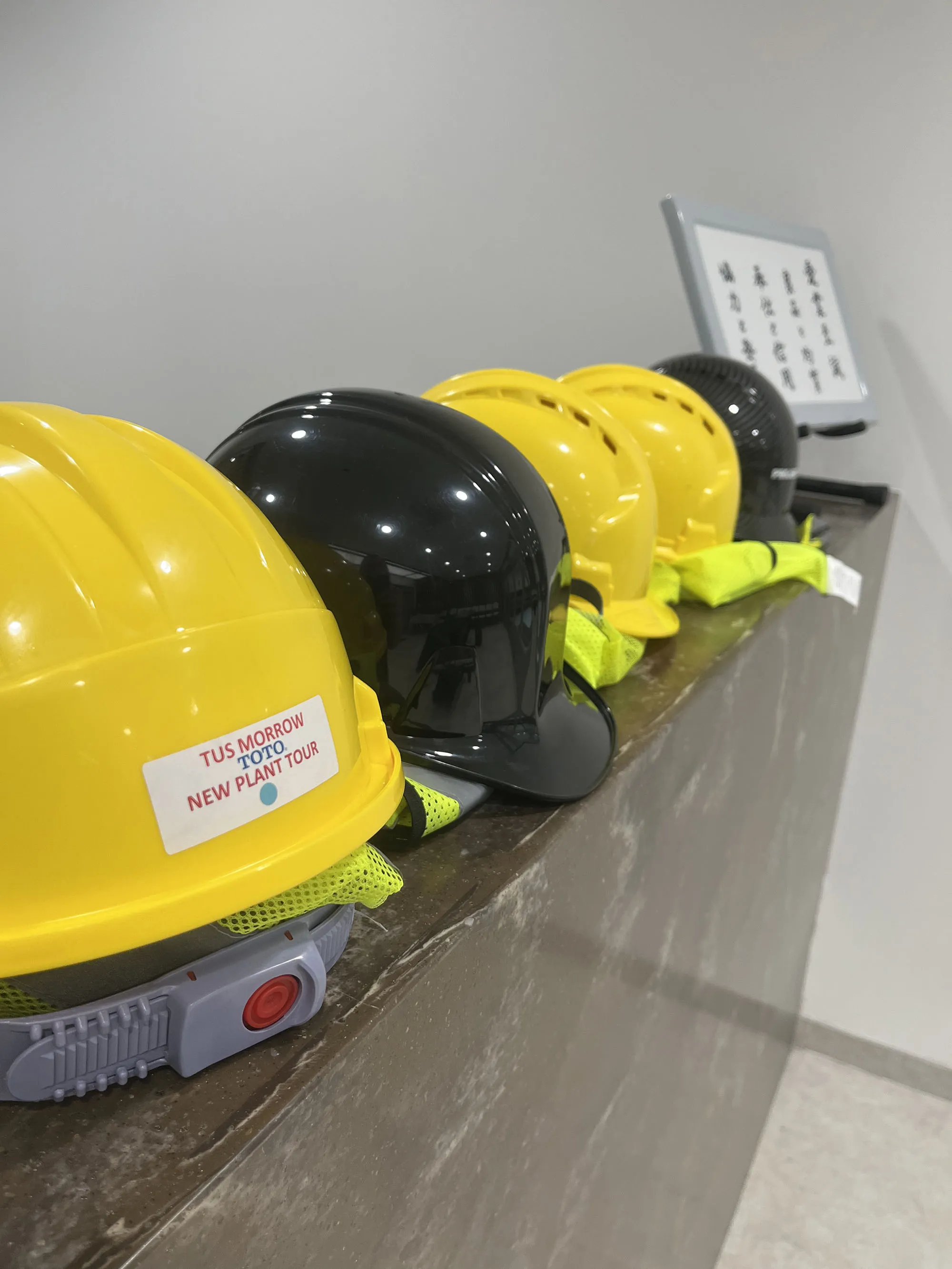 Yellow and black hard hats lined up for guests ahead of the TOTO Morrow facility plant tour during the ribbon-cutting event.